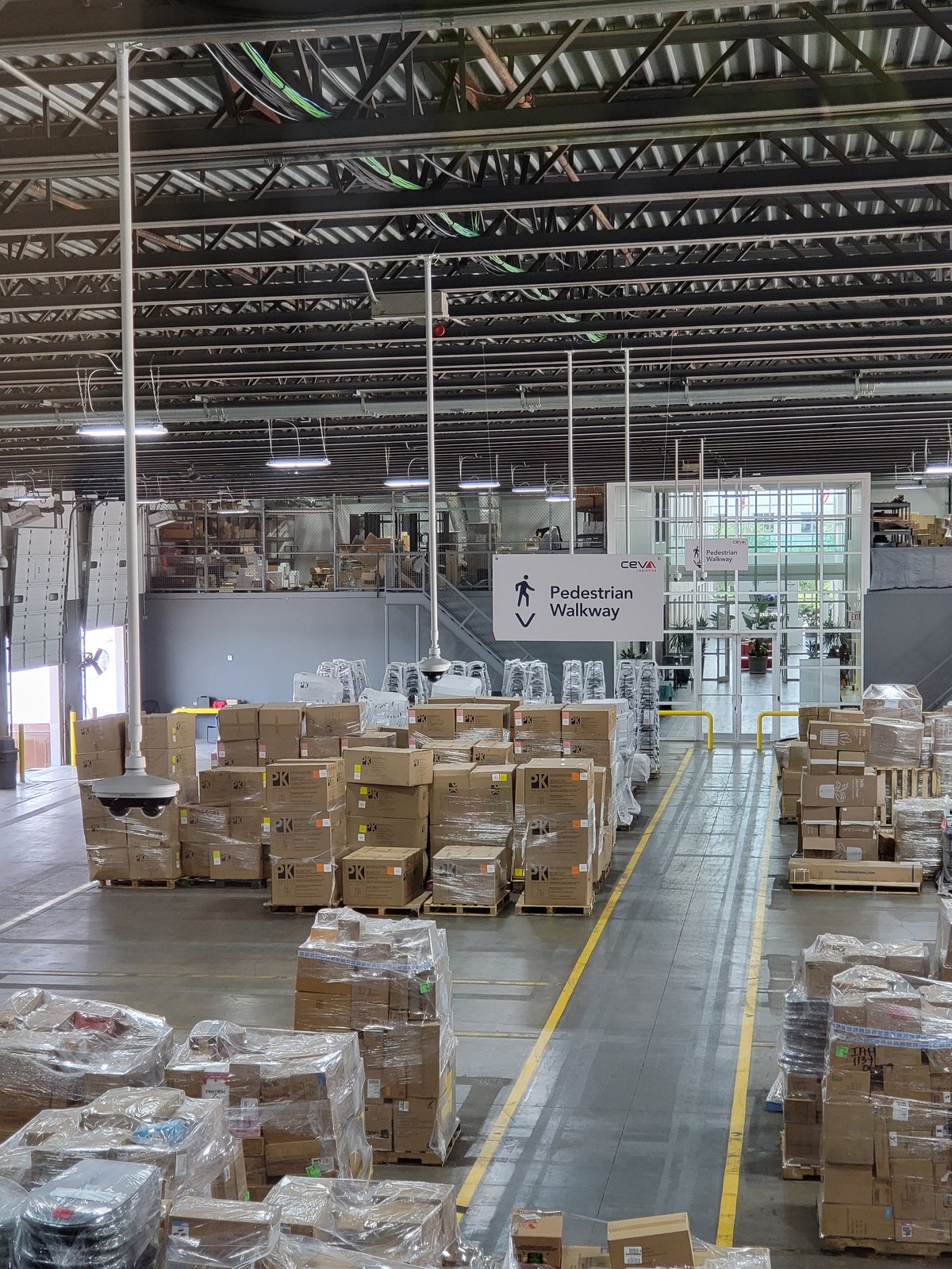 Large warehouse interior with stacked cardboard boxes and packages organized on a floor with yellow safety line markings