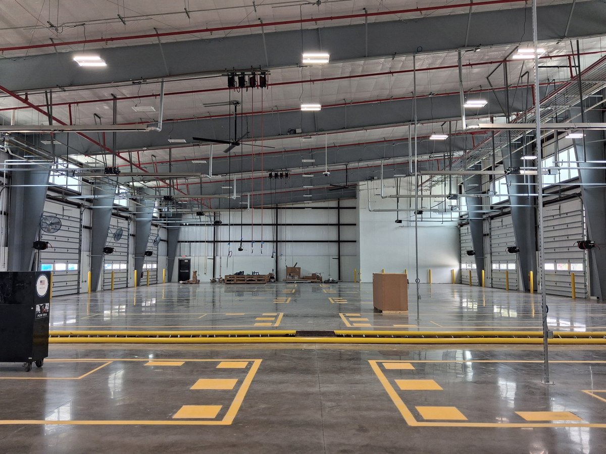 Empty warehouse interior with yellow safety markings on polished concrete floor and industrial ceiling