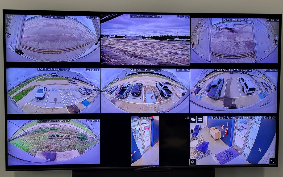 Security camera monitoring display showing multiple CCTV feeds from various parking lot and facility views on a grid layout