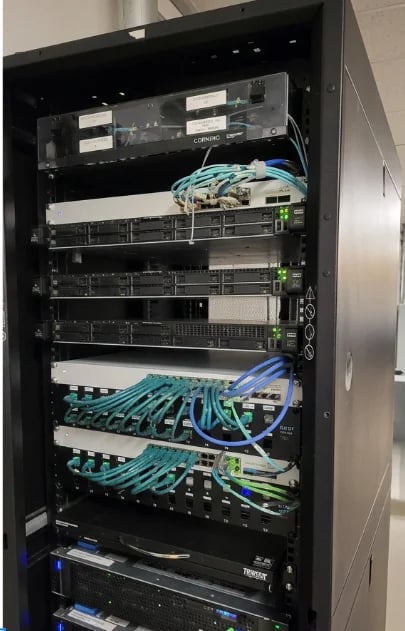 Network server rack with multiple hardware units, cables, and blue network connections organized in a black cabinet